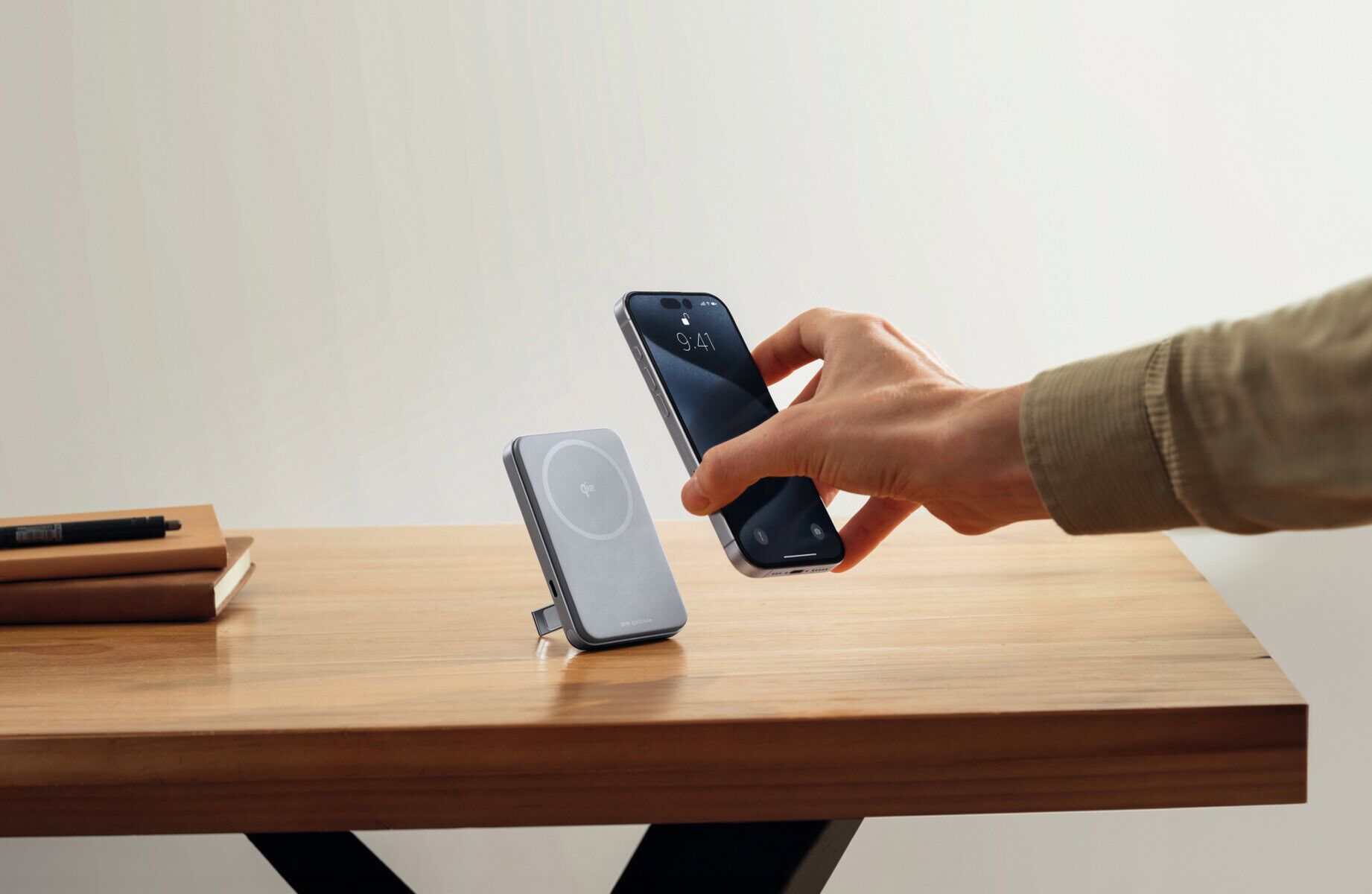 Wireless charging pad and smartphone on wooden desk with books, showcasing portable power solutions from EcoFlow IE.